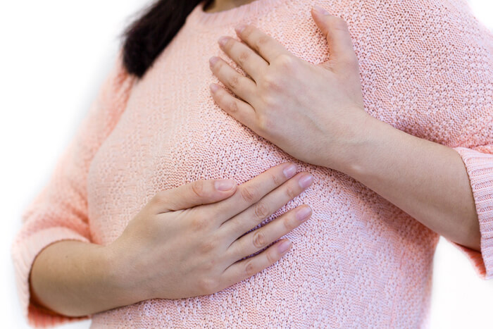 Mujer con mastitis poniendo sus manos sobre la zona inflamada