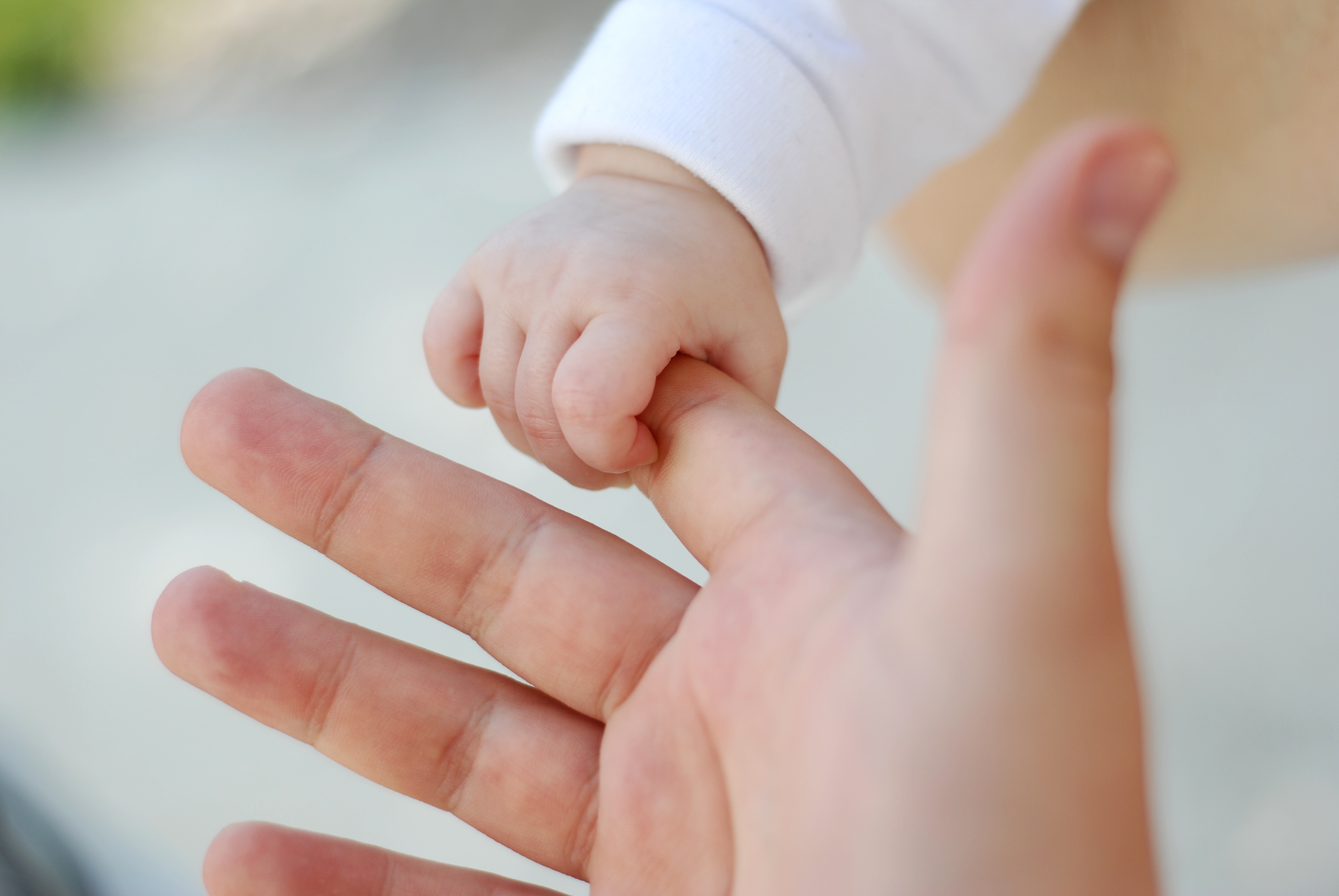 Mano de bebé cogiendo el dedo de un adulto. 
