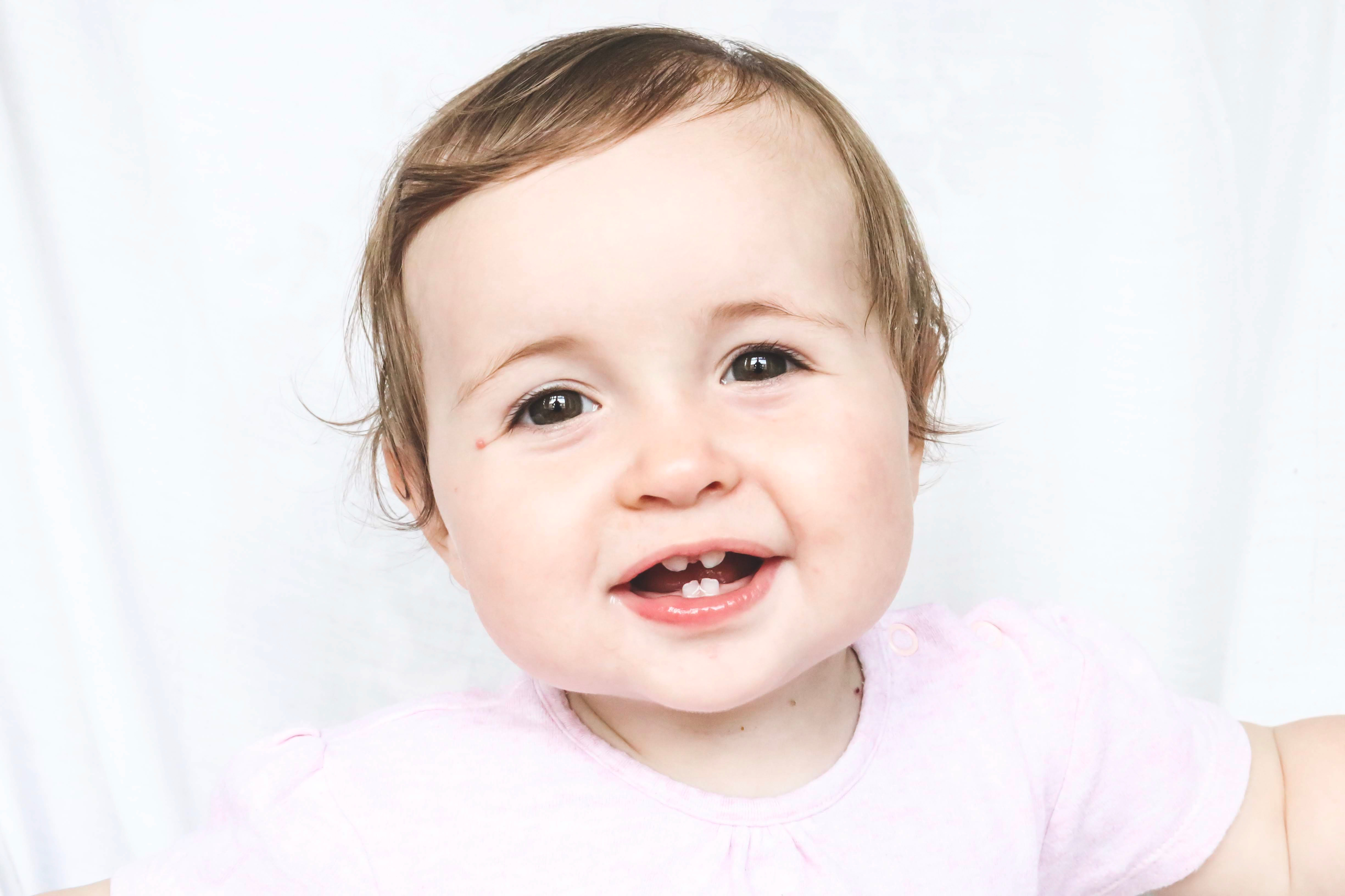 Bebé sonriente mostrando cuatro dientes de leche