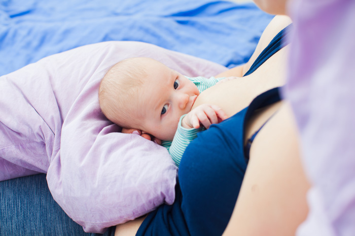 Madre con mastitis dando el pecho a su bebé en posición de rugby