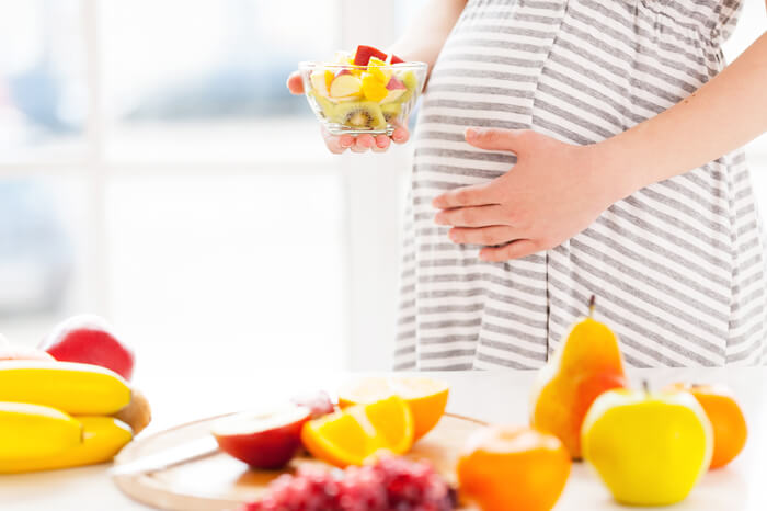Mujer embarazada comiendo fruta