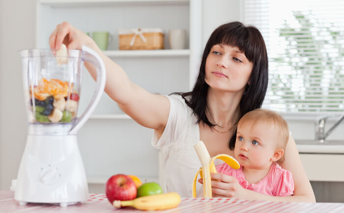 Madre preparando papilla de frutas con su bebé