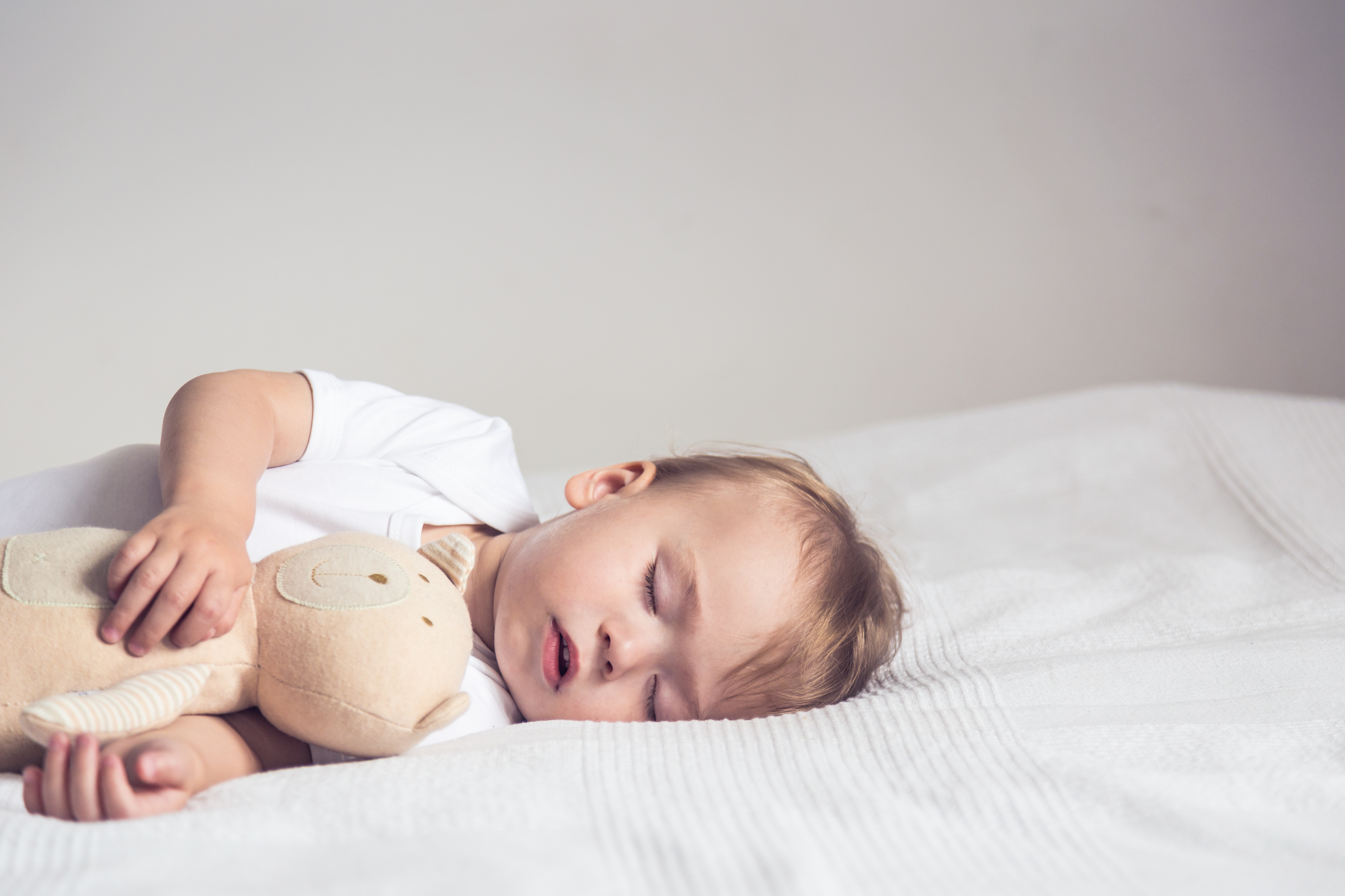 Niño durmiendo en la cuna con un muñeco